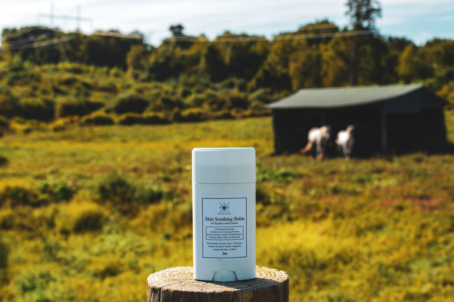 Product packaging on a wooden stump with a scenic background of a field and trees.