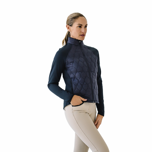 Woman wearing a navy quilted jacket and beige pants on a white background
