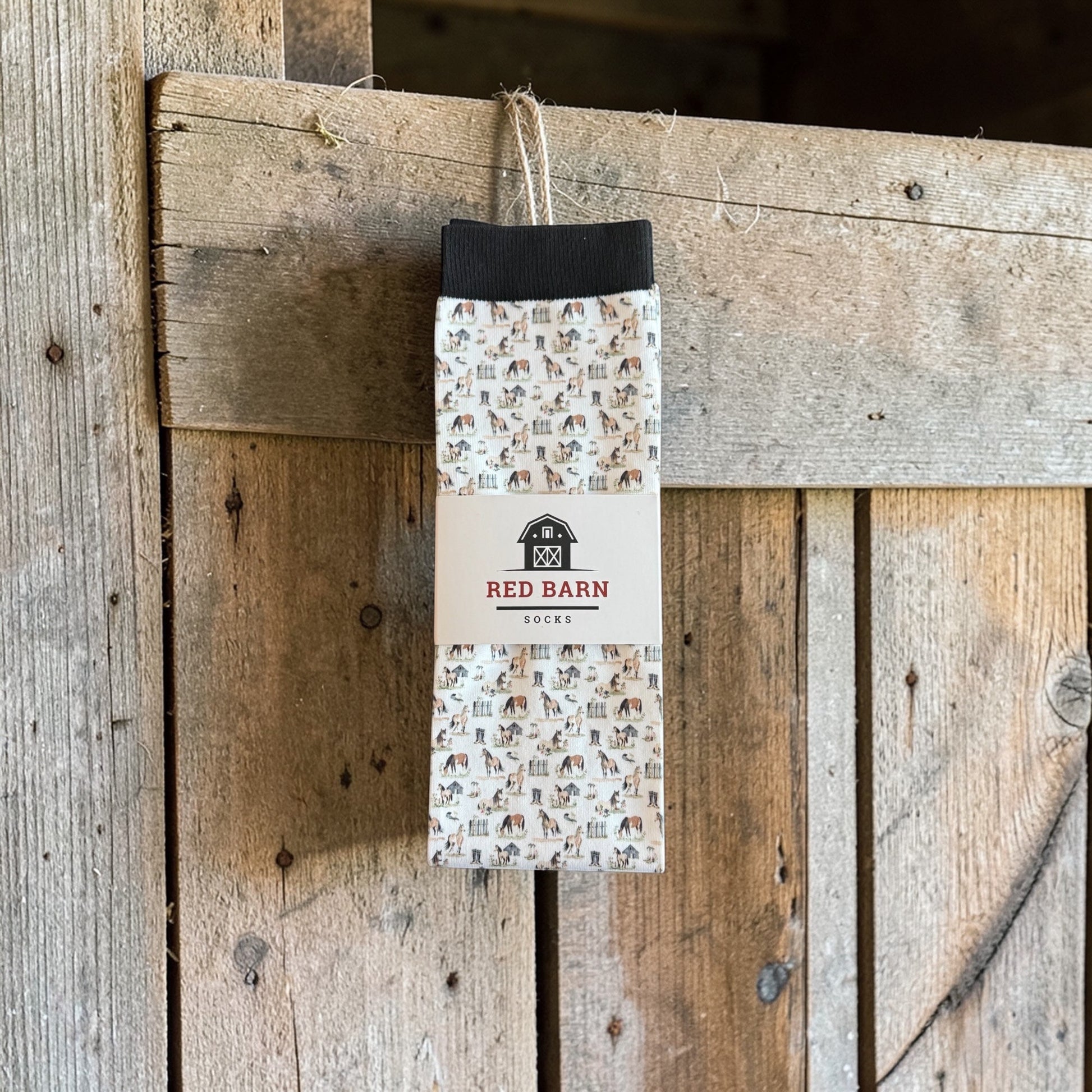 Pair of socks with a pattern hanging on a wooden background, featuring the 'Red Barn' brand.
