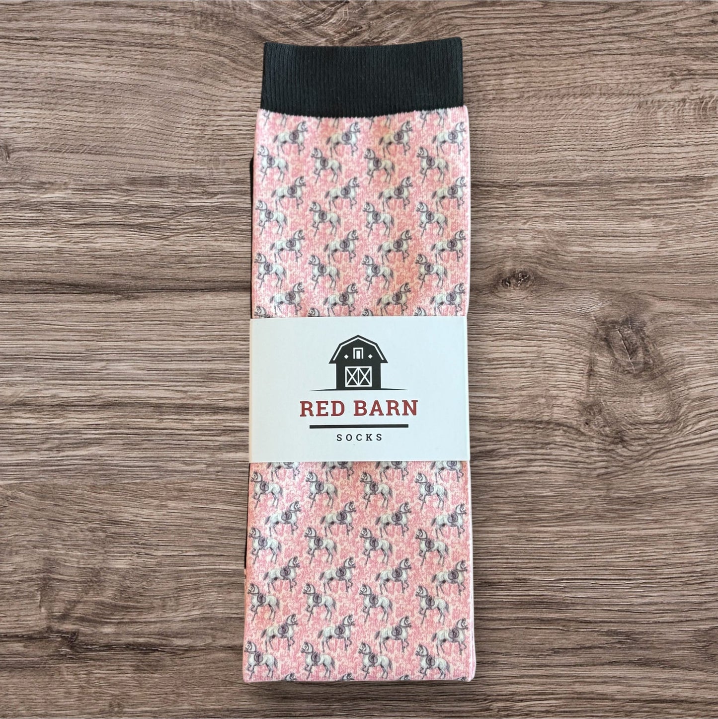 Pack of socks with horse pattern and Red Barn Socks label on a wooden surface