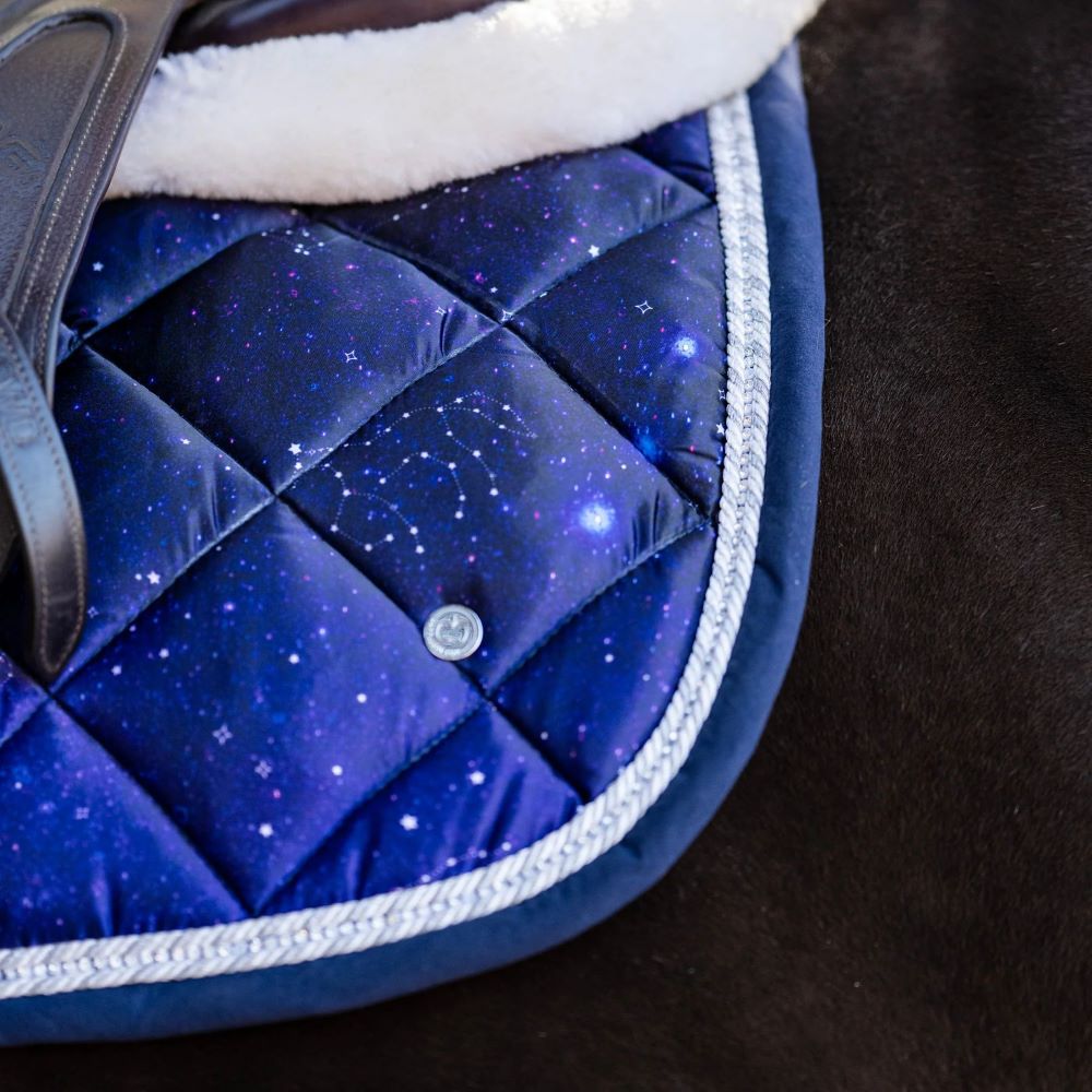Close-up of a blue quilted saddle pad with star pattern on a dark background