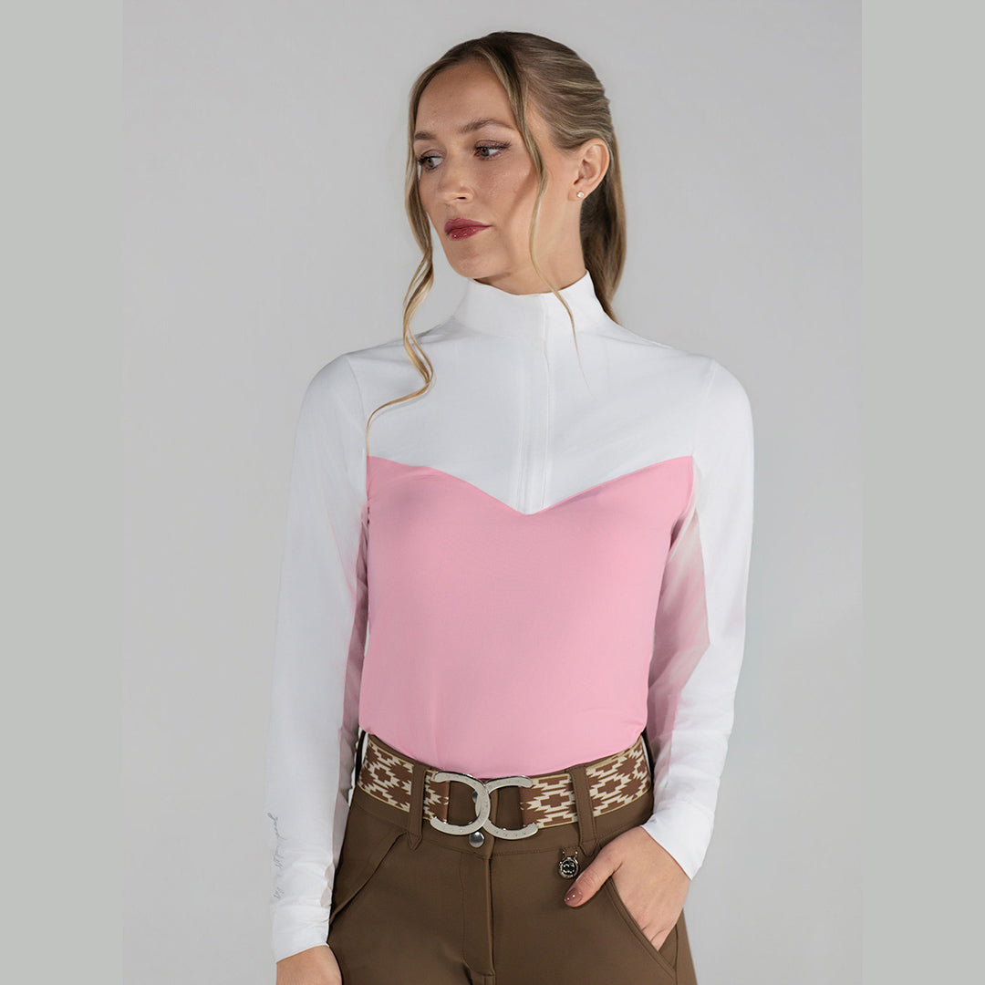 Woman wearing a white and pink top with brown pants on a plain background
