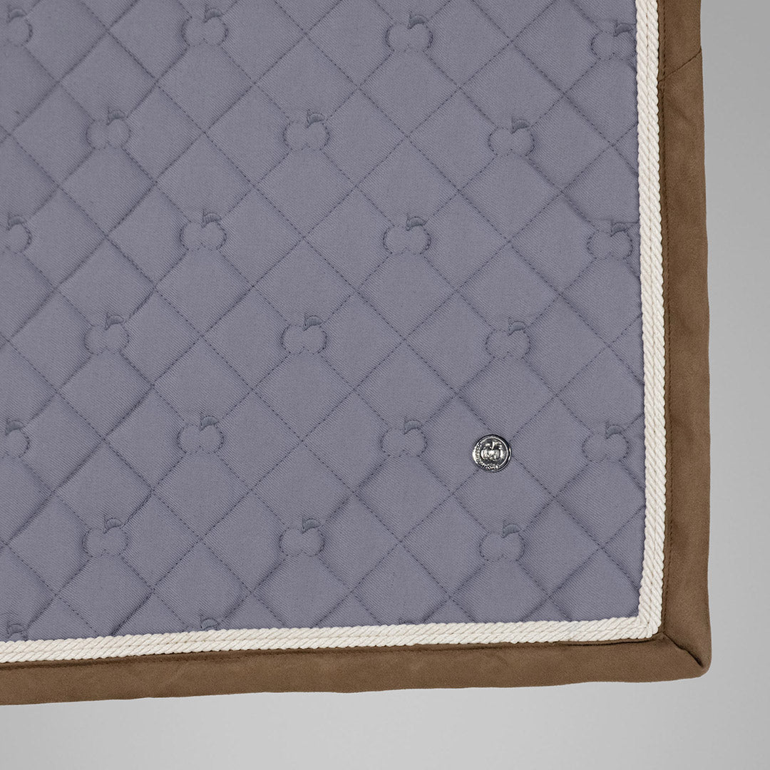 Quilted blanket with diamond pattern and brand logo on a light gray background