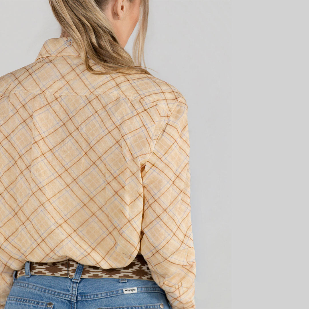 Person wearing a beige plaid shirt and blue jeans on a plain background