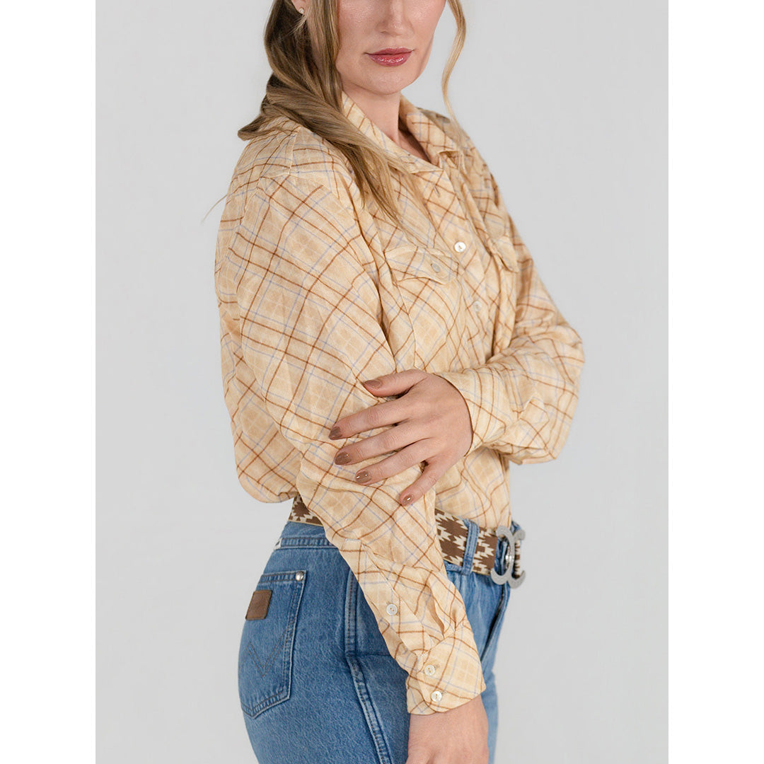 Woman wearing a beige plaid shirt and blue jeans on a gray background