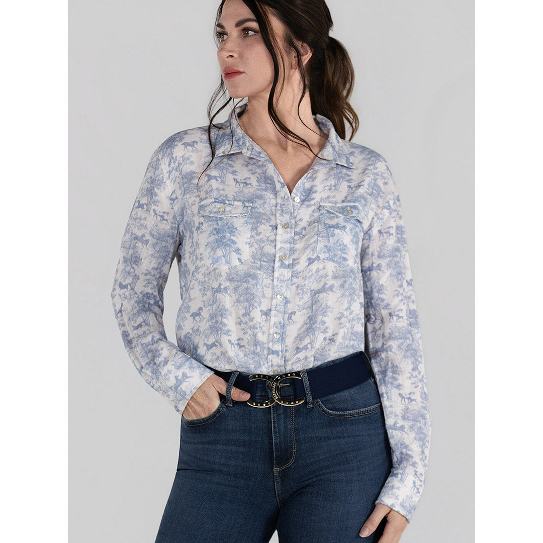 Woman wearing a light blue floral shirt and dark jeans on a gray background