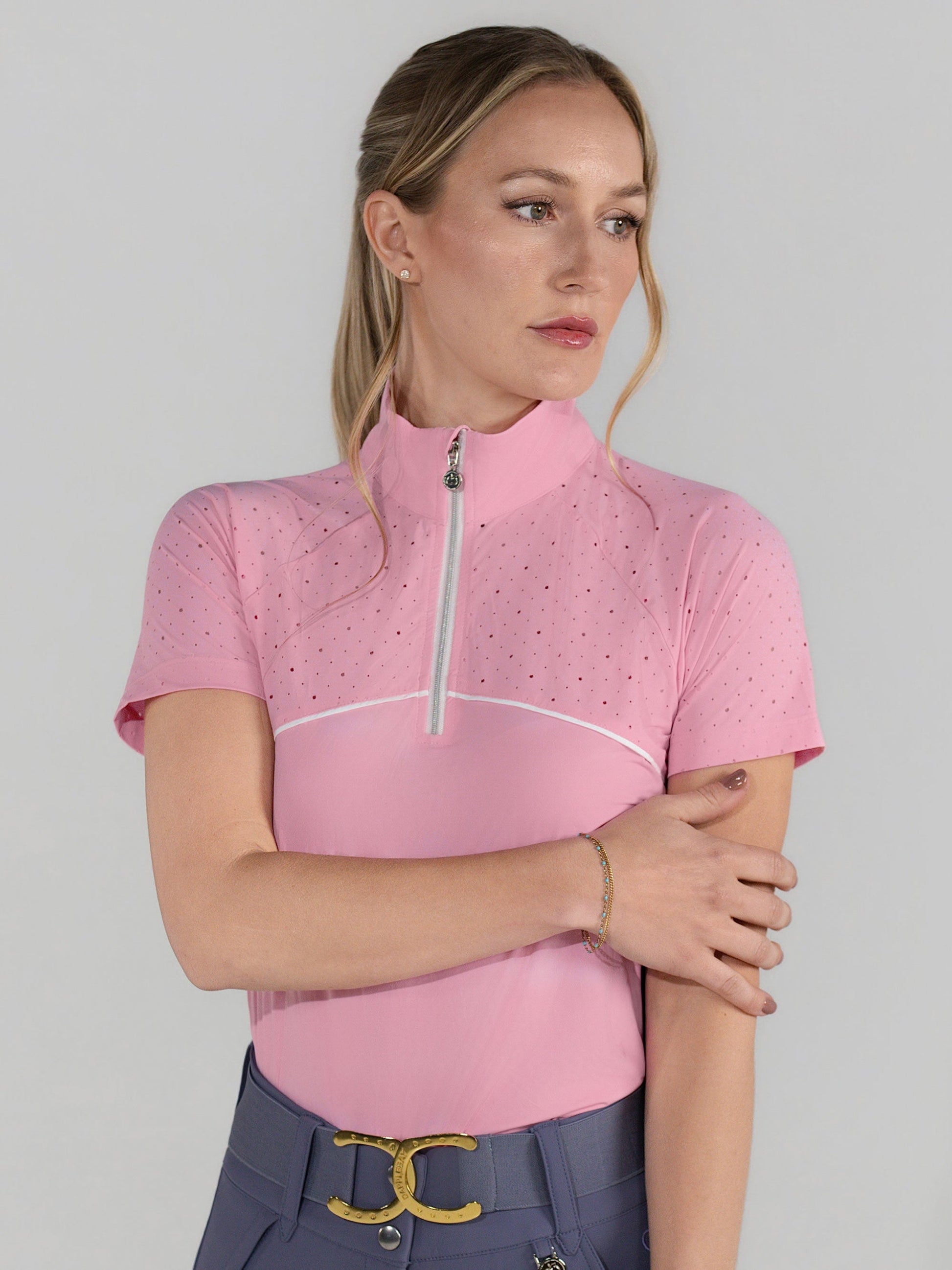 Woman wearing a pink polo shirt with a zipper on a plain background