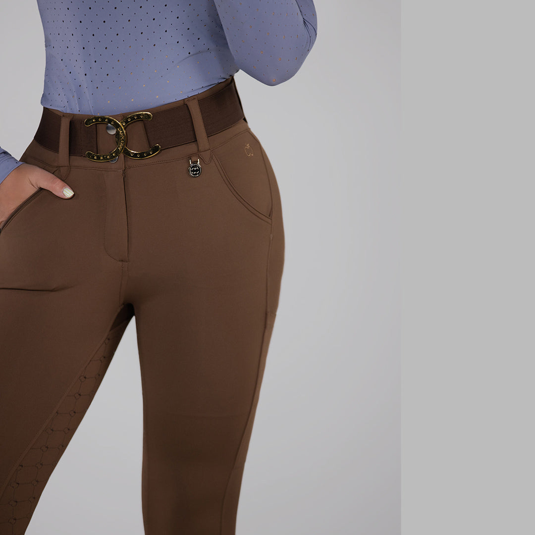 Brown riding pants with a gold belt on a plain background
