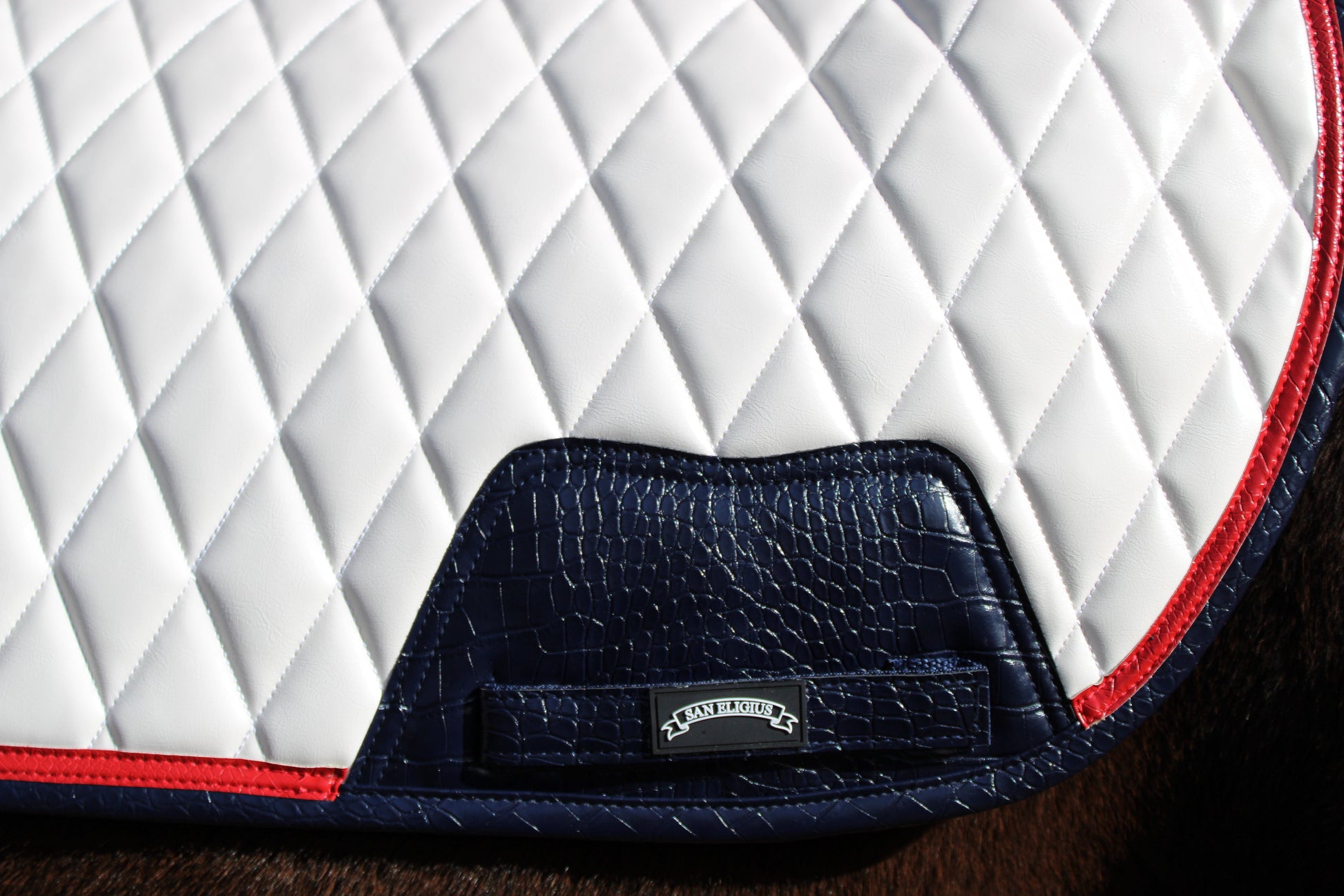 Close-up of a quilted equestrian saddle pad with a brand logo.