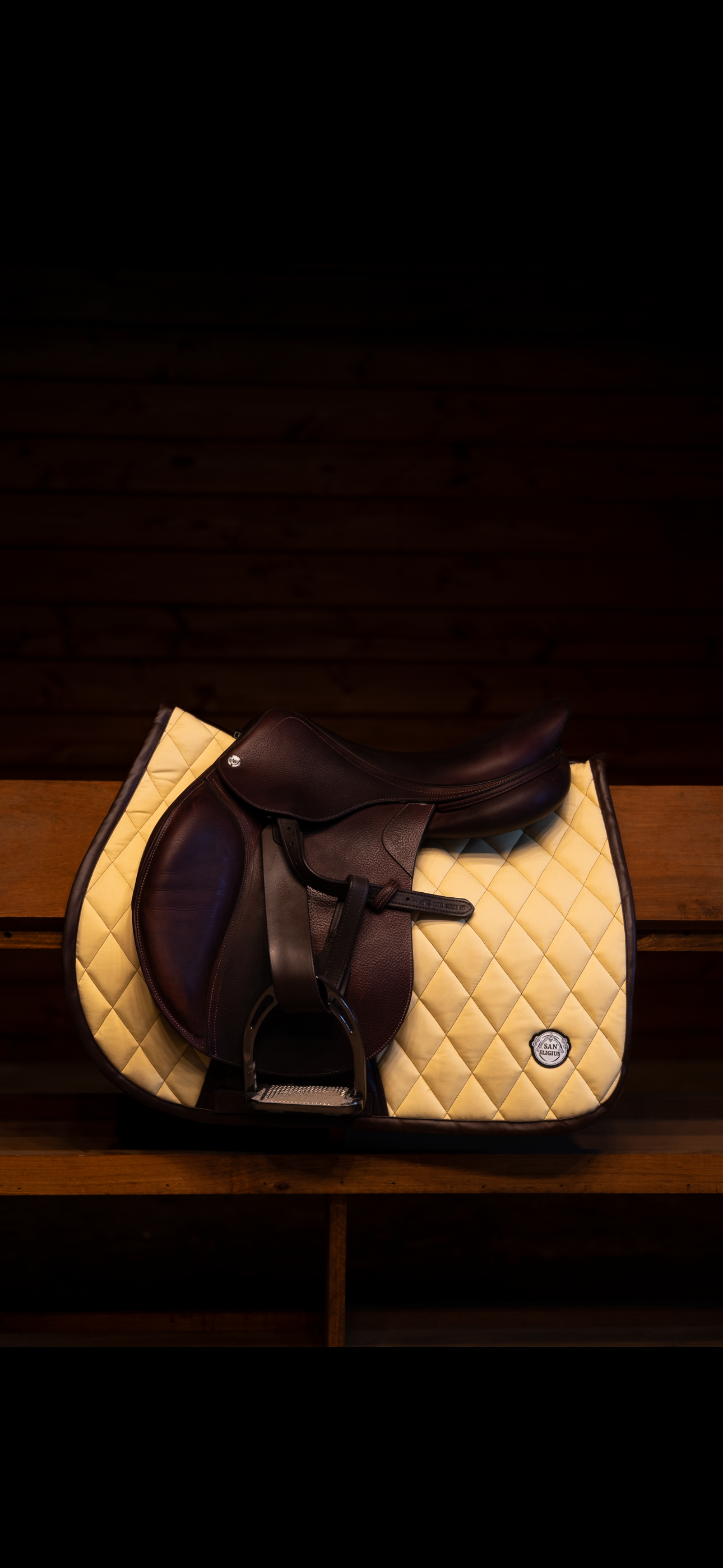 Brown and beige quilted saddle pad on a wooden surface