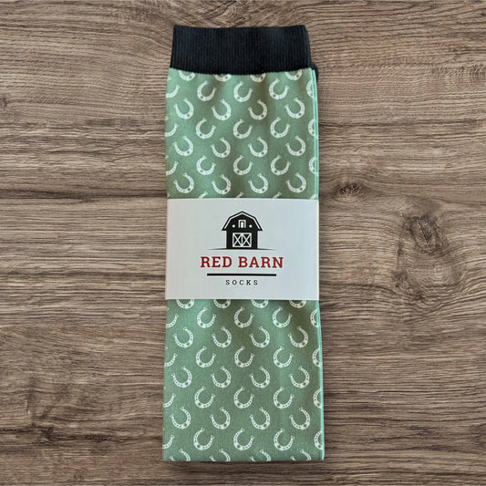 Green sock with horse shoe pattern and Red Barn Socks label on a wooden surface