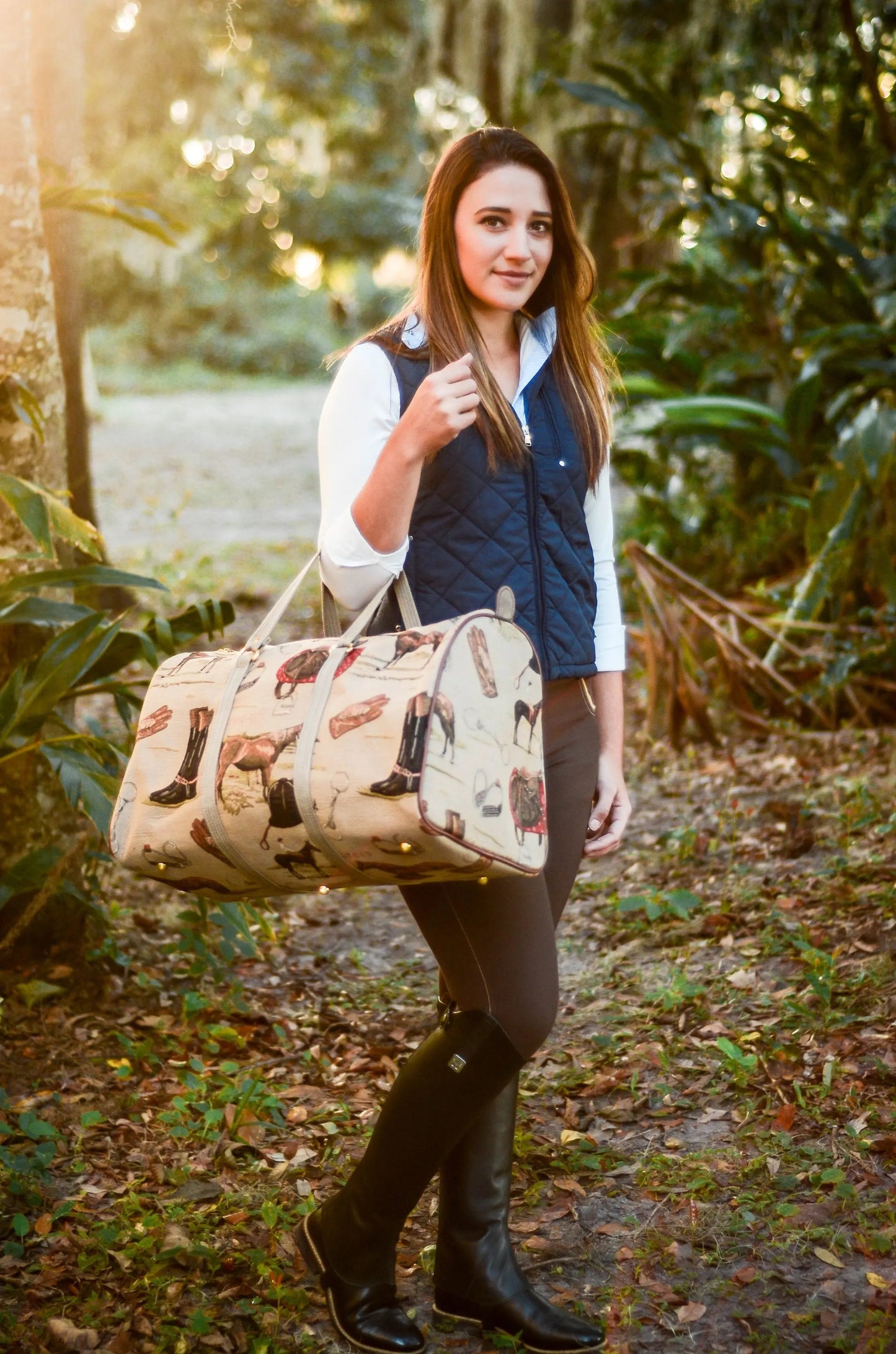 Woman holding a patterned duffel bag in a forest setting