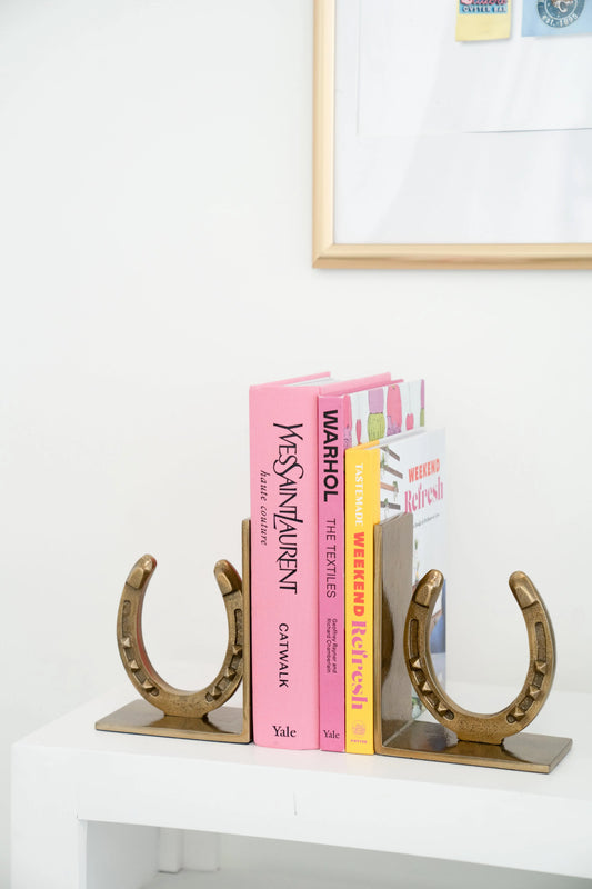 Horseshoe-shaped bookends holding books on a white surface.