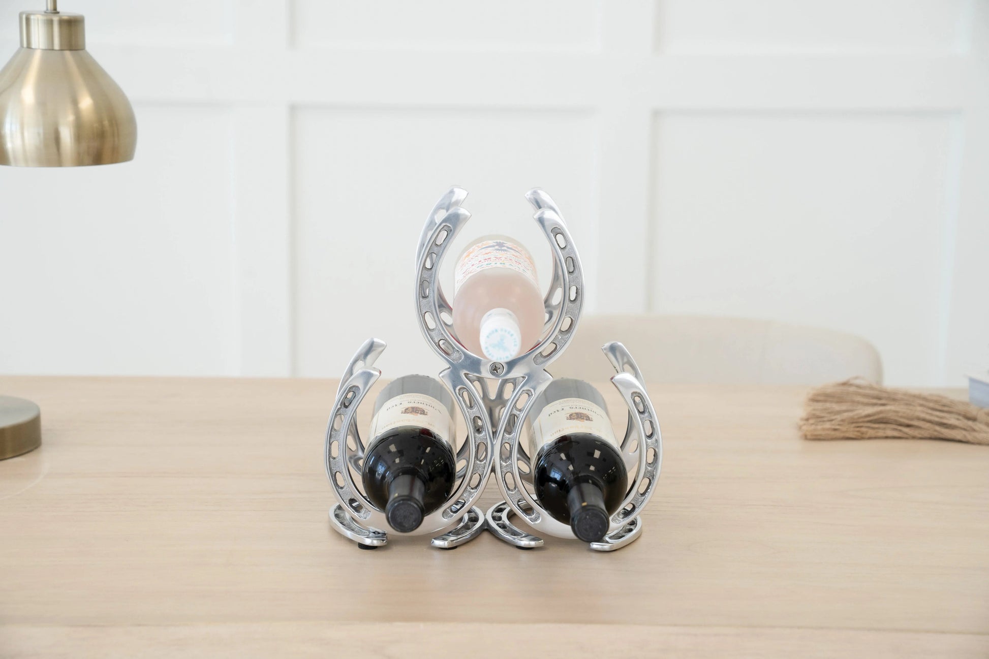 Decorative wine bottle holder shaped like horseshoes on a wooden surface.