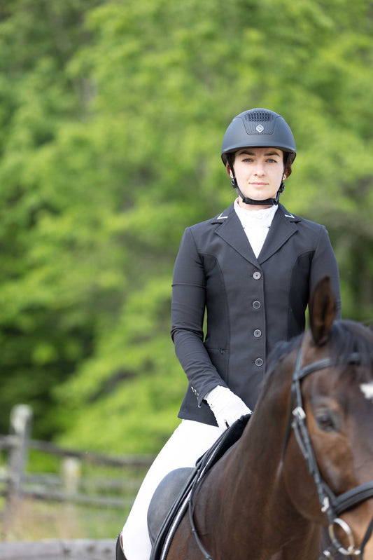 Person in equestrian attire riding a horse with a blurred green background