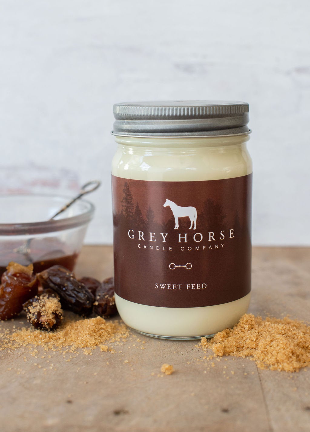 Jar of 'Sweet Feed' candle from Grey Horse Candle Company on a wooden surface with dried fruits.