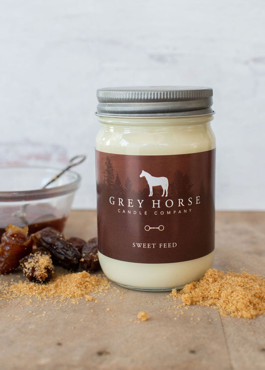 Jar of 'Sweet Feed' candle from Grey Horse Candle Company on a wooden surface with dried fruits.